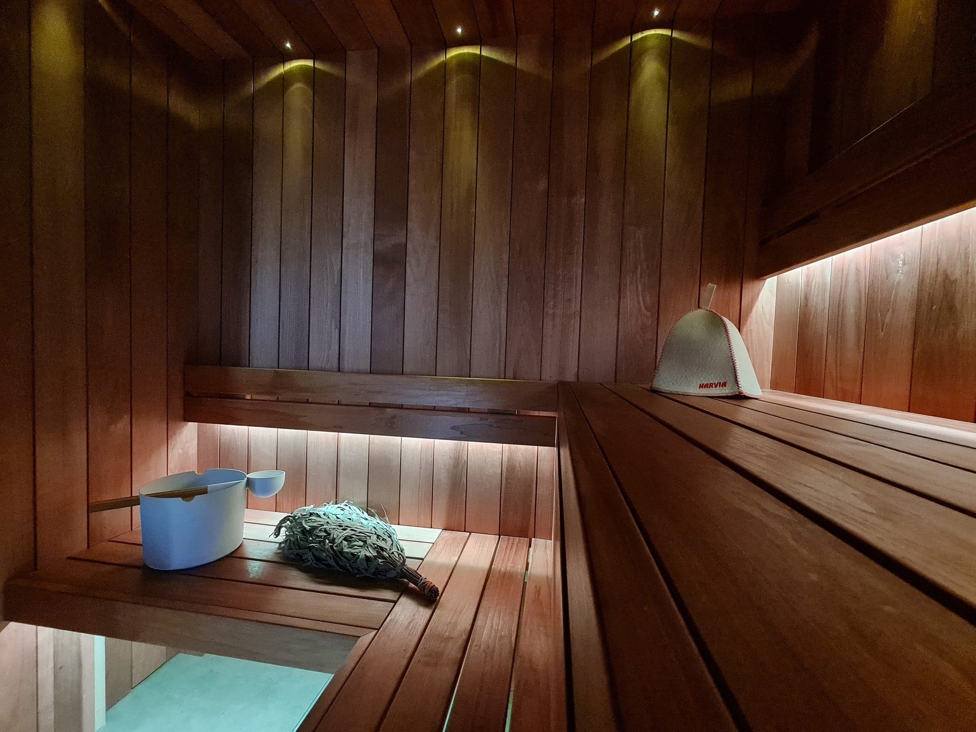 The sauna in warm light: two tiers of timber benches, lit from beneath